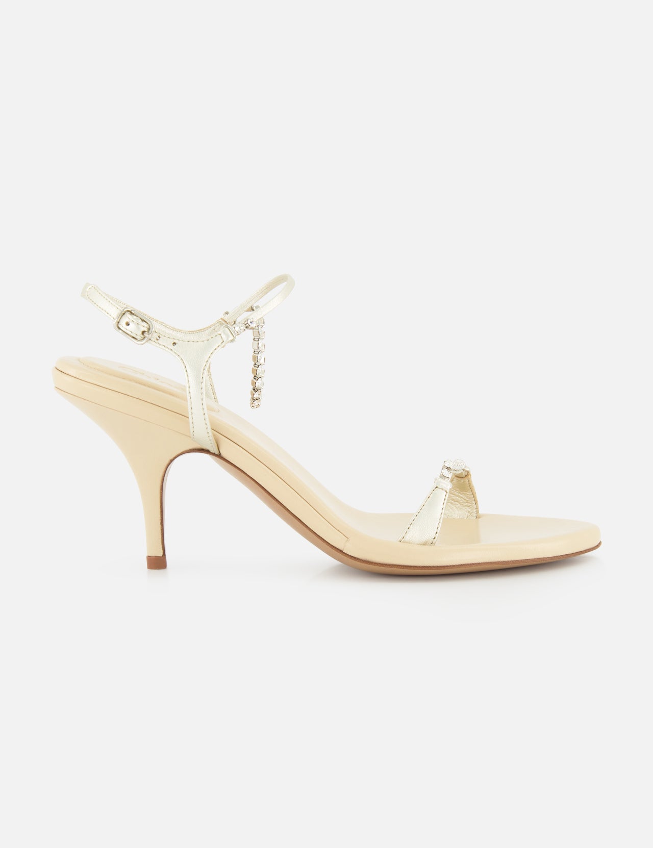 The Zia Crystal Chain Heels by CHLOÉ are elegant beige heeled sandals featuring a slim ankle strap with a delicate buckle and an open toe, crafted in the refined style of classic Italian designer shoes and displayed in profile against a plain white background.