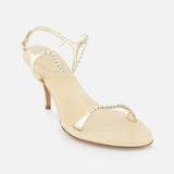 The Zia Crystal Chain Heels by CHLOÉ feature gold heels with slender straps embellished with sparkling rhinestones, a closed heel, and an open toe design, beautifully capturing the allure of Italian designer footwear and displayed against a white background.