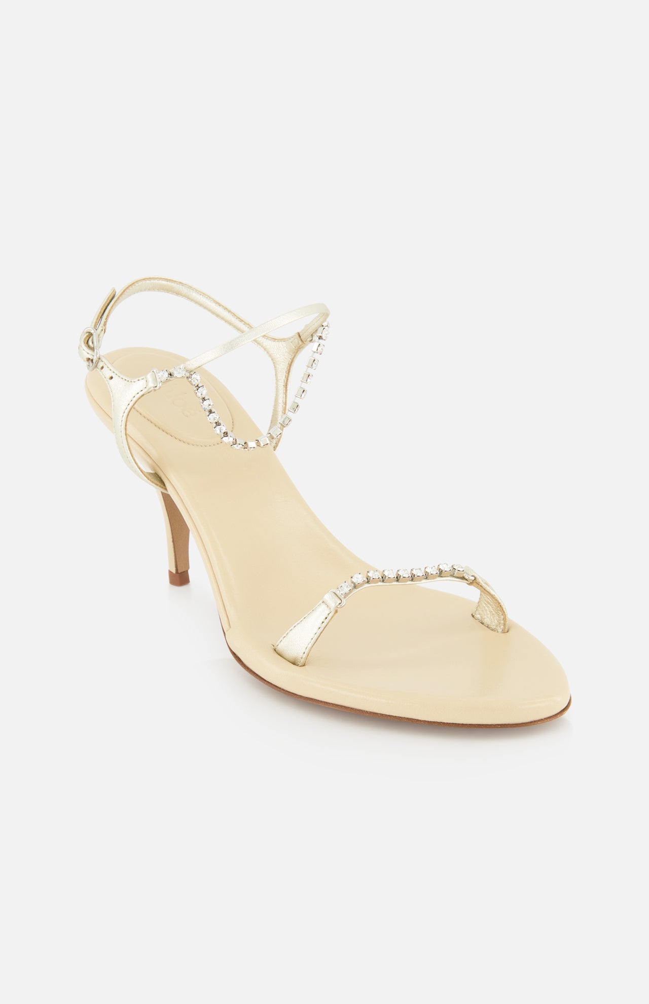 The Zia Crystal Chain Heels by CHLOÉ feature gold heels with slender straps embellished with sparkling rhinestones, a closed heel, and an open toe design, beautifully capturing the allure of Italian designer footwear and displayed against a white background.