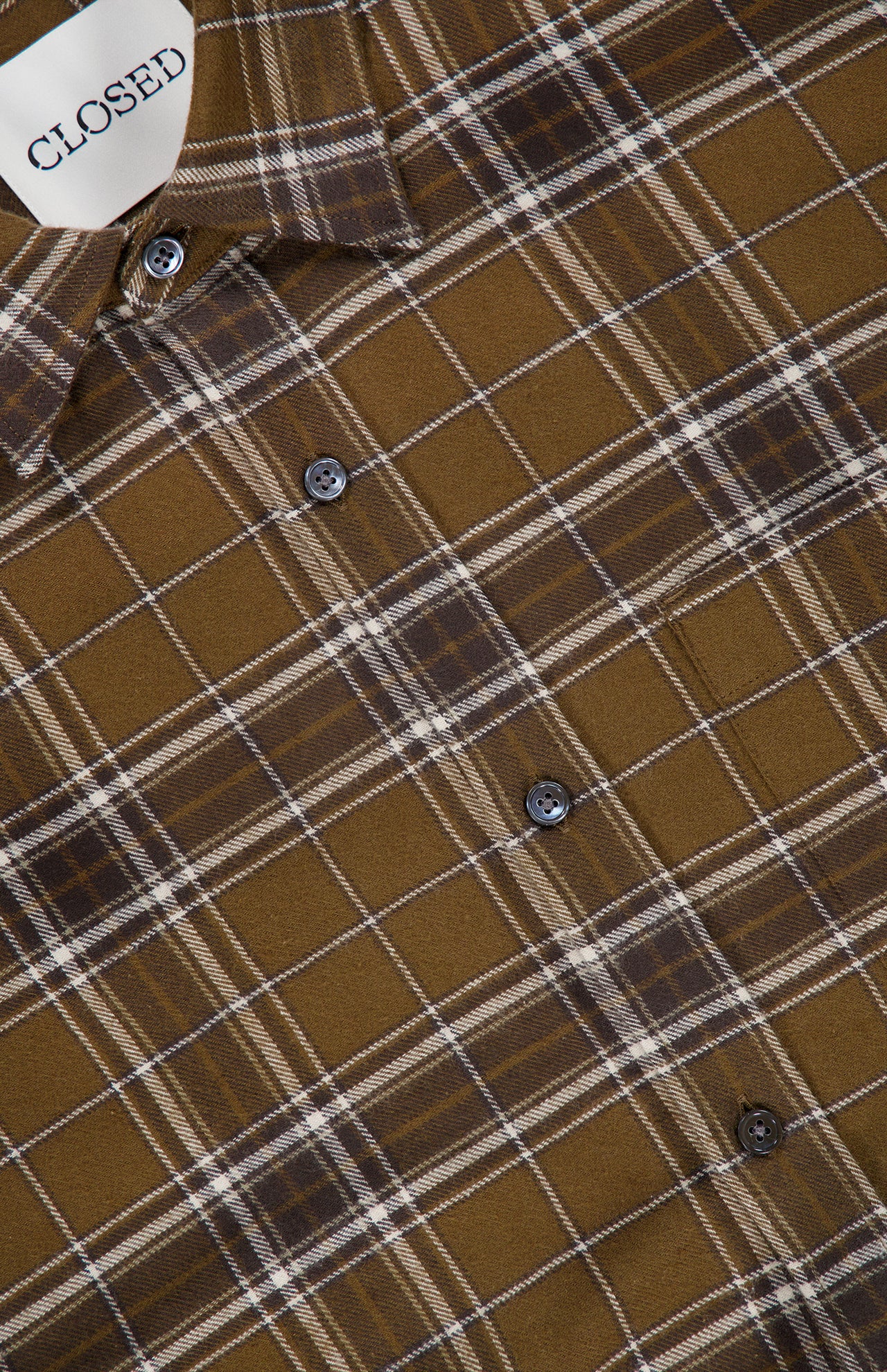 A close-up of the Basic Plaid Shirt by CLOSED, featuring a brown plaid pattern with white and gray lines, crafted from soft cotton. The shirt displays the CLOSED brand tag and has several visible buttons down the front—making it an ideal fall shirt for men.