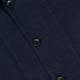 Close-up of a navy blue button-up shirt with three dark buttons and a hint of a white tag—ideal for pairing with the CLOSED Linen Cargo Jacket, thanks to its classic button-front design.