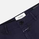 Close-up of the waistband of Classic Chino Shorts by CLOSED, made from dark navy stretch cotton twill with belt loops, a button closure, and an inner white label reading CLOSED. The smooth fabric has a slight sheen.