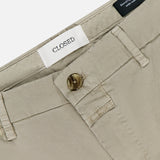 Close-up of Classic Chino Shorts by CLOSED in stretch cotton twill, featuring a button closure, belt loops, and a white brand label sewn inside the waistband with part of a black inner label also visible.