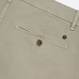 Close-up of the back pocket of CLOSED Classic Chino Shorts in beige stretch cotton twill, featuring a button closure, visible belt loops, and a small metal tag above the pocket.