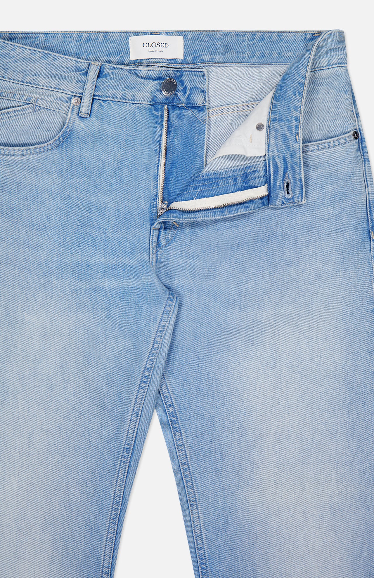 The Cooper True Straight Leg Denim jeans by CLOSED are crafted from sustainable denim in Italy. Shown here in light blue, the jeans feature a straight leg silhouette with the fly partially unzipped to reveal the inner fabric and button closure. The waistband displays a CLOSED-branded tag, and the jeans are laid flat on a white background.
