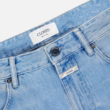 Close-up of the waistband and top front of the Cooper True Straight Leg Denim jeans in light blue by CLOSED, featuring a branded label, button, belt loops, and part of the front pockets against a white background. Crafted from sustainable denim and made in Italy.