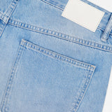 Close-up of the back pocket and waistband of light blue Cooper True Straight Leg Denim jeans by CLOSED, with a blank white label above the pocket. The fabric texture and stitching details are clearly visible, highlighting the high-quality craftsmanship characteristic of these Italian-made sustainable jeans.