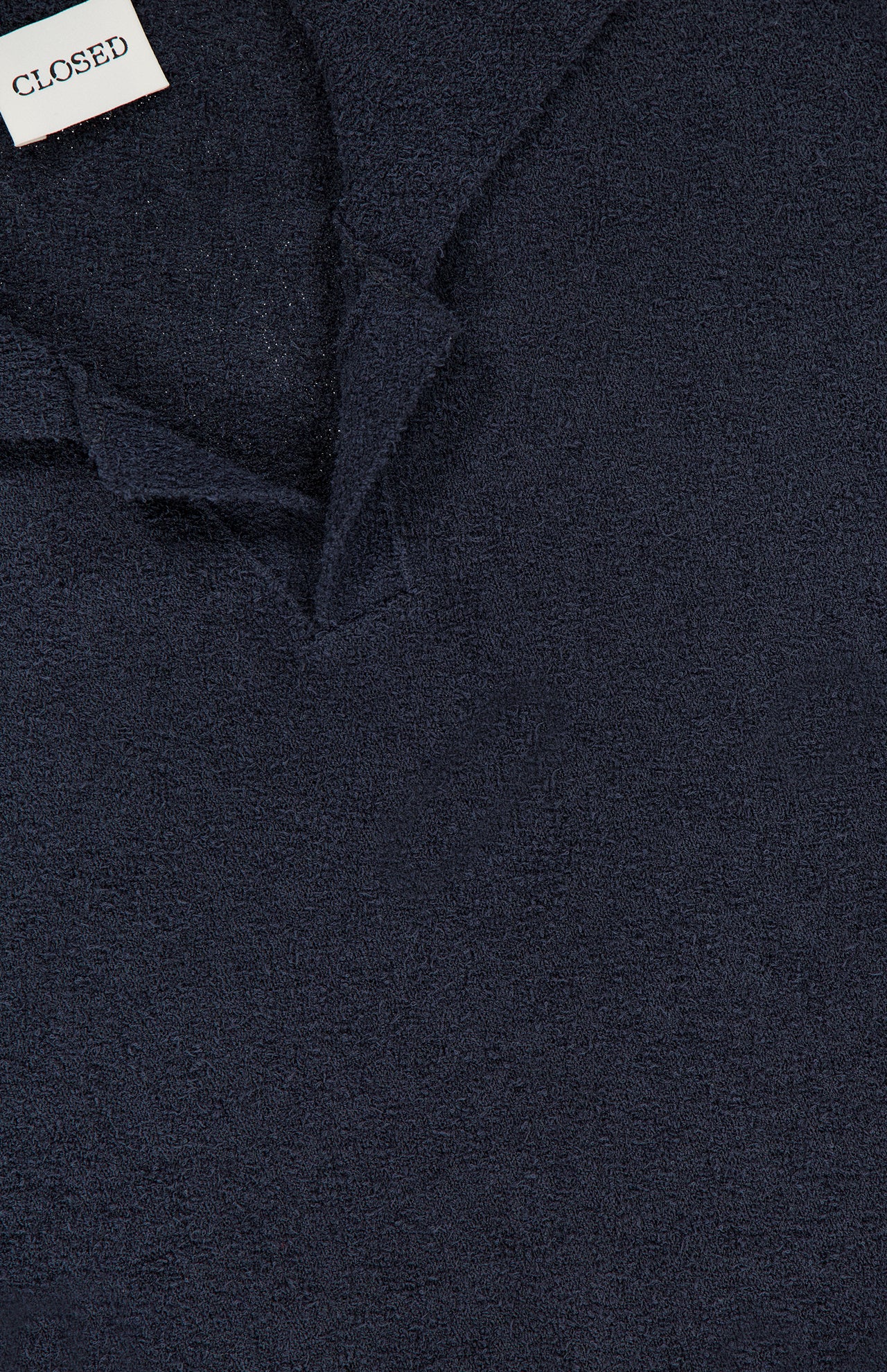 Close-up of the French Terry Johnny Collar Polo Shirt by CLOSED in dark navy textured fabric, featuring a Johnny collar and a white label displaying the brand name.