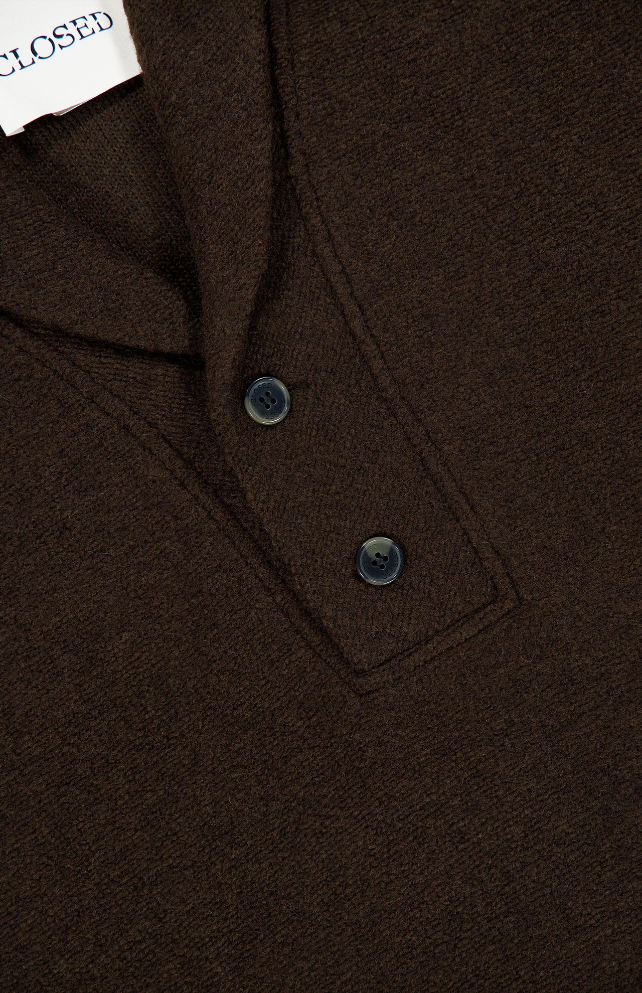 Close-up of the CLOSED Shawl Collar Sweater in chocolate brown, showcasing its textured finish, two black buttons near the collar, and a partially visible white tag with black text.