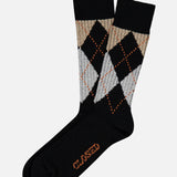 A pair of Argyle Socks by CLOSED in black melange, featuring a gray, beige, and orange multicolored argyle pattern. “CLOSED” is printed in orange on the soles for a preppy collegiate accent.