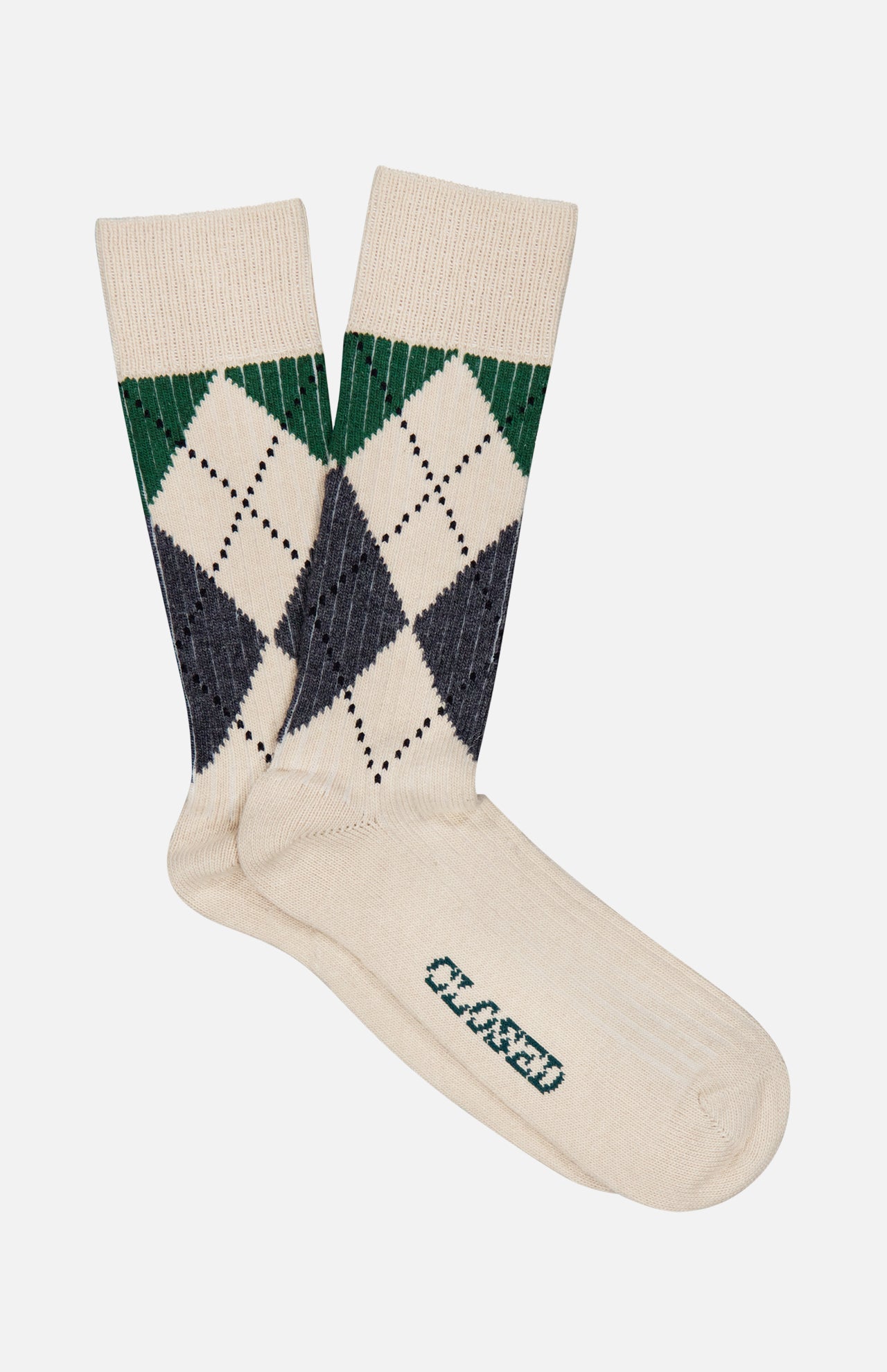 A pair of CLOSED Argyle Socks in a cream color, featuring a green and navy argyle pattern near the top and the word “CLOSED” printed in green on the sole.