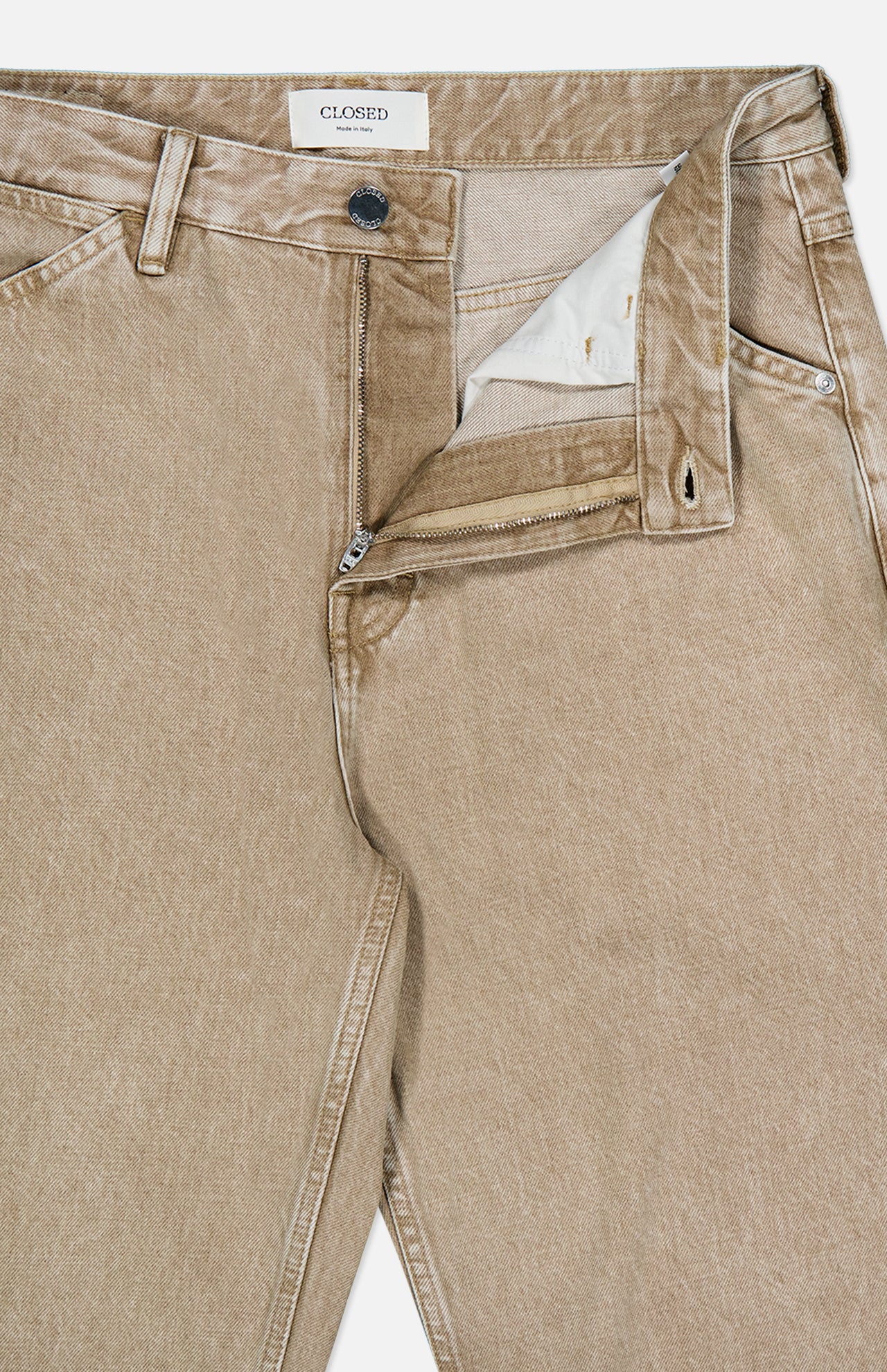 The Shoreham Wide Pant by CLOSED are beige denim jeans with a partially open zipper and visible button fly, revealing the inside label that reads CLOSED. These wide fit jeans are designed with belt loops and front pockets for a classic look.