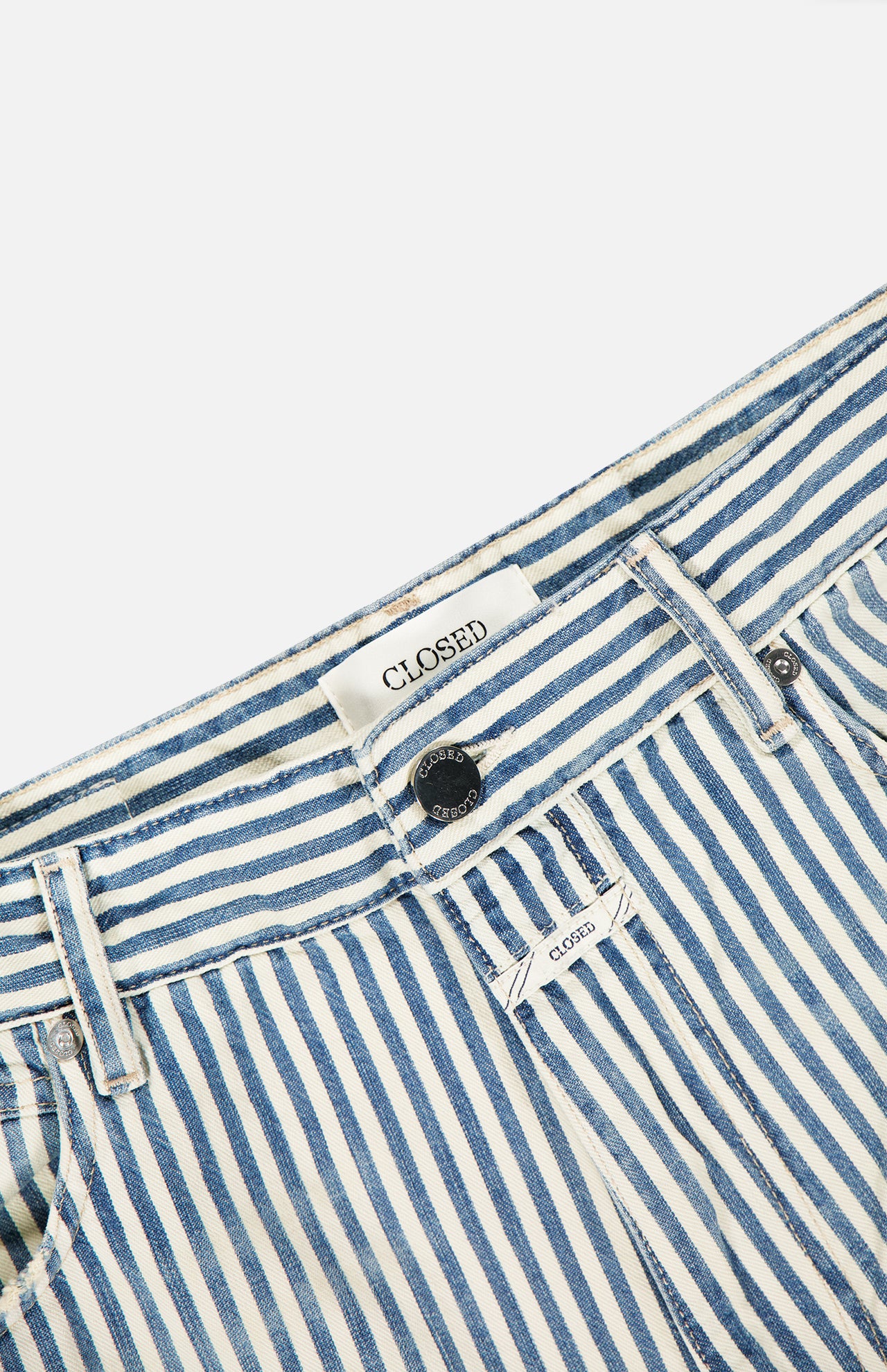 Close-up of CLOSED Springdale Relaxed Stripe Pants—blue and white vertical stripes, 100% cotton denim, made in Italy, with belt loops, front button, and an inner waistband label reading CLOSED.