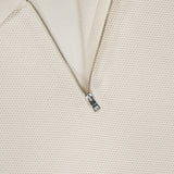 Close-up of the Zipped Neck Polo Shirt by CLOSED, crafted from textured cream cotton with a partially open silver half-zip and a white CLOSED label at the collar.