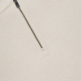 Close-up of the Zipped Neck Polo Shirt by CLOSED, featuring cream textured cotton, a partially open silver zip at the neck, and a white collar label with CLOSED in black uppercase letters.