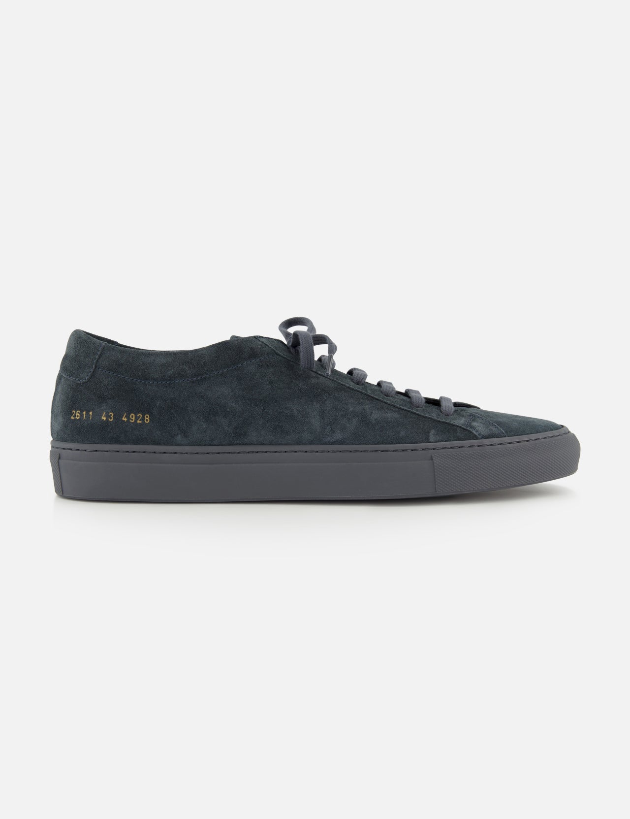 The COMMON PROJECTS Achilles Suede Premium Sneakers in dark navy feature a minimalist design with black laces, a gray rubber sole, and gold numbers stamped on the heel, displayed in a side profile view against a white background.