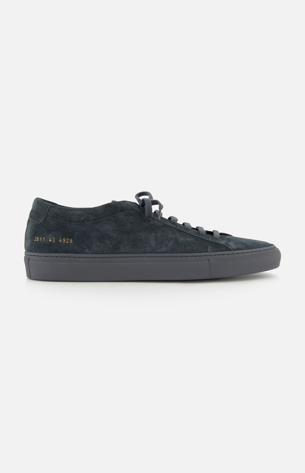 The COMMON PROJECTS Achilles Suede Premium Sneakers in dark navy feature a minimalist design with black laces, a gray rubber sole, and gold numbers stamped on the heel, displayed in a side profile view against a white background.