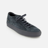 COMMON PROJECTS Achilles Suede Premium Sneakers in dark gray, featuring a luxury suede low-top design with matching laces and a rubber sole, displayed at an angle from above on a plain white background.