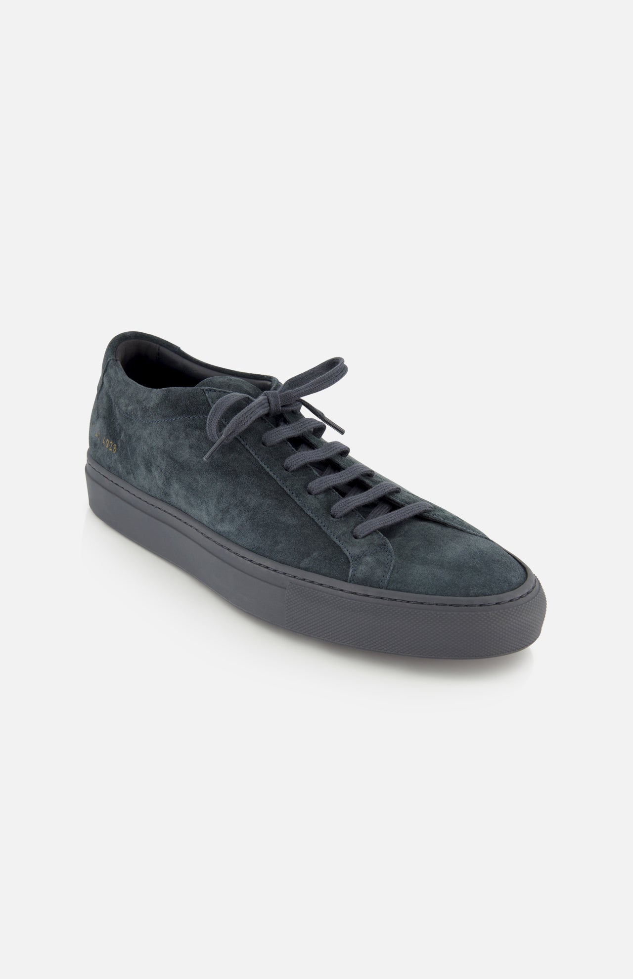 COMMON PROJECTS Achilles Suede Premium Sneakers in dark gray, featuring a luxury suede low-top design with matching laces and a rubber sole, displayed at an angle from above on a plain white background.