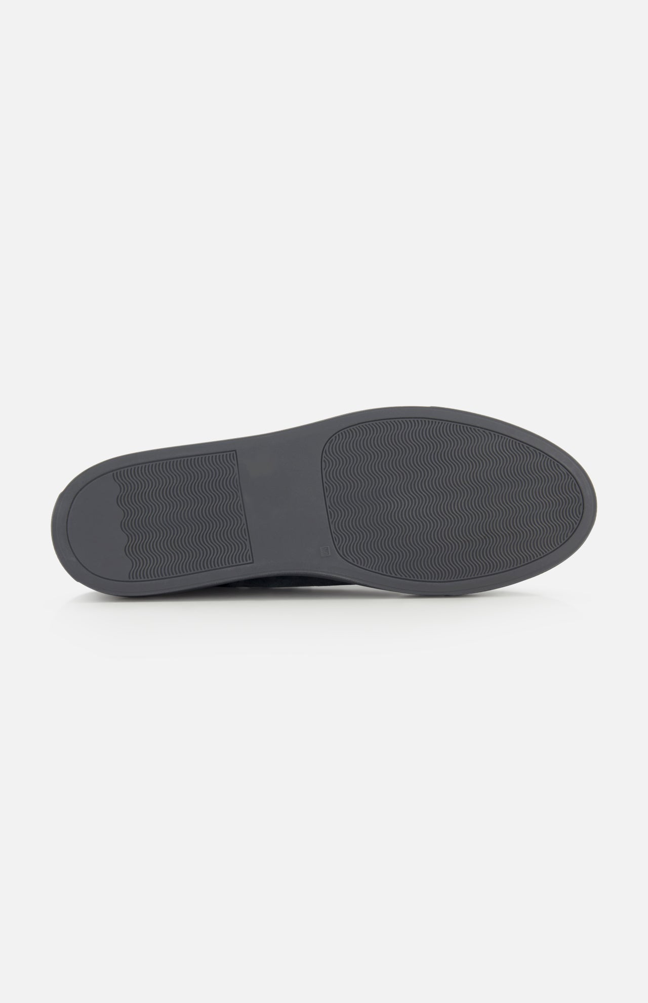 The image displays the bottom view of the COMMON PROJECTS Achilles Suede Premium Sneakers in dark gray, featuring a minimalist sole design with a textured, non-slip pattern and a rectangular section with horizontal lines at one end.