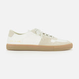 The Bball Duo Leather and Suede Sneaker by COMMON PROJECTS is a luxury low-top shoe crafted from off-white leather with beige suede panels, featuring white laces, a beige rubber sole, and gold numbers printed near the heel on the outer side.