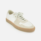 The COMMON PROJECTS Bball Duo Leather and Suede Sneaker is a luxury low-top shoe in white and beige, featuring premium suede and off-white leather panels, white laces, and a tan rubber sole, showcased against a plain white background.