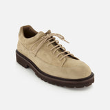 The COMMON PROJECTS Hiker Low Suede Piuma Boot is shown in beige suede with a dark brown, rugged textured sole and visible stitching, viewed from the front left angle on a white background.