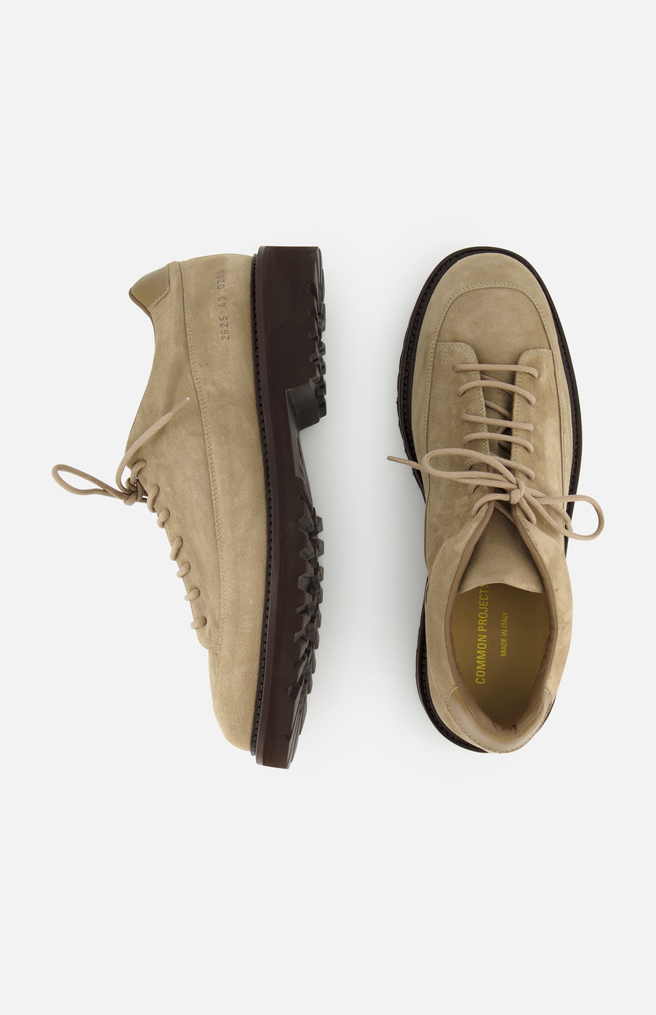 A pair of COMMON PROJECTS Hiker Low Suede Piuma Boots in beige suede, featuring chunky dark brown soles, is displayed from the side and top view against a white background.