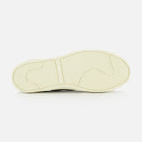 The image displays the outsole of the COMMON PROJECTS Premium Skate In Nubuck Sneaker, set horizontally against a white background. The off-white sole features a herringbone traction pattern and multiple grip-enhancing grooves, demonstrating the meticulous craftsmanship characteristic of luxury low-top footwear.