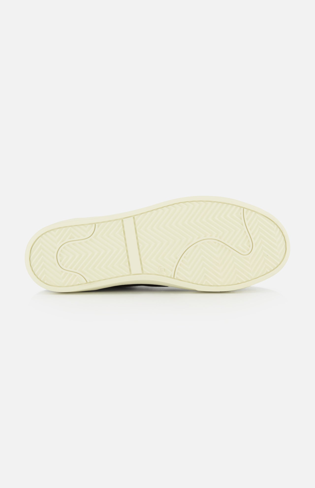 The image displays the outsole of the COMMON PROJECTS Premium Skate In Nubuck Sneaker, set horizontally against a white background. The off-white sole features a herringbone traction pattern and multiple grip-enhancing grooves, demonstrating the meticulous craftsmanship characteristic of luxury low-top footwear.