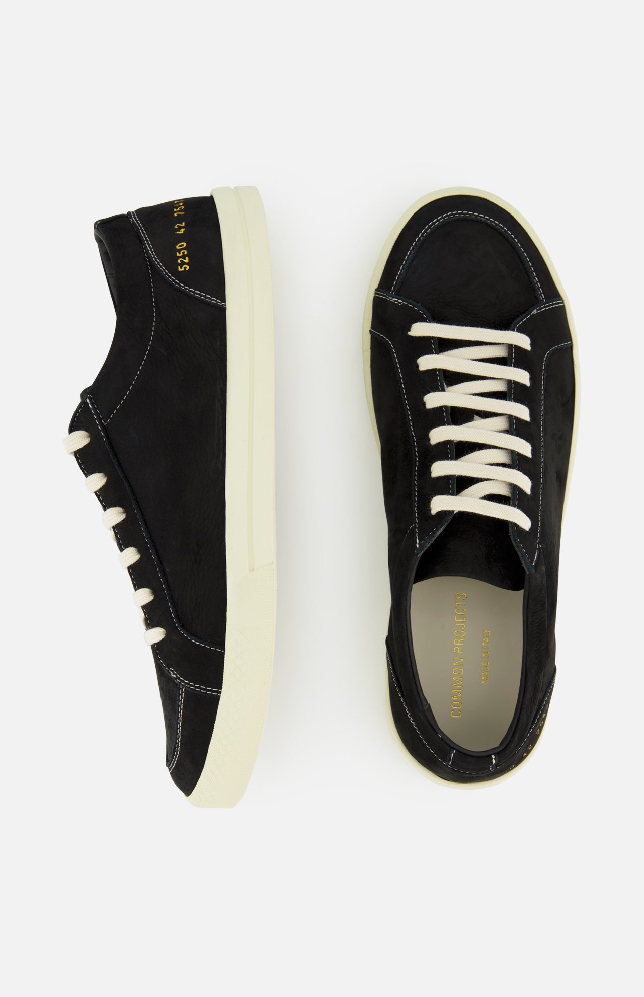 A pair of COMMON PROJECTS Premium Skate In Nubuck Sneakers in black, featuring white soles and white laces, is displayed from top and side angles against a plain light background. These luxury low-top sneakers blend classic style with modern sophistication.