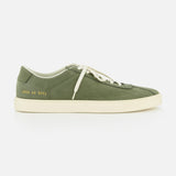 The COMMON PROJECTS Leather Tennis Sneaker is a luxury army green street shoe with white laces, a clean white sole, minimalist design, and a small gold serial number on the heel. Photographed against a plain white background.