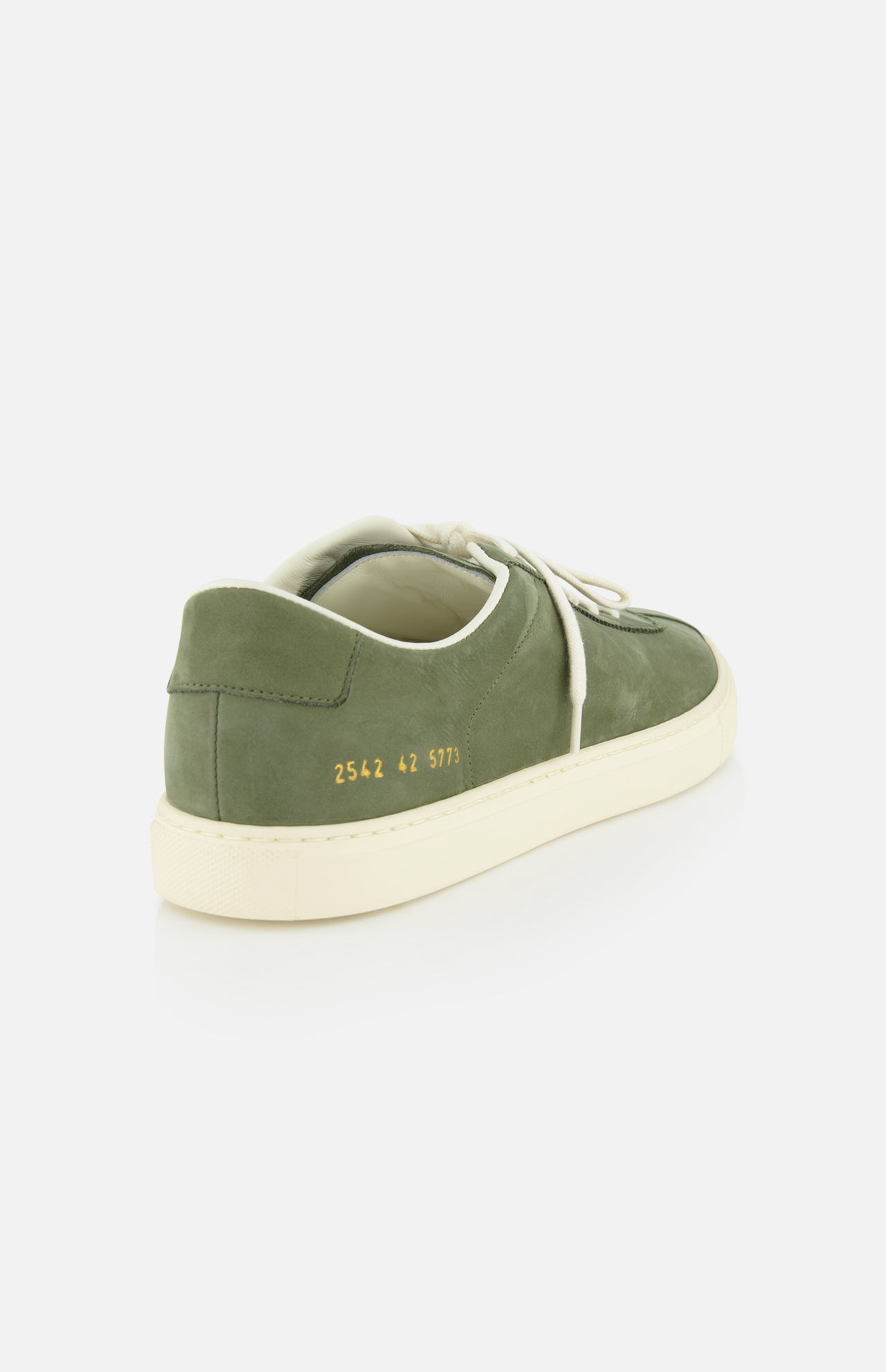 The Leather Tennis Sneaker by COMMON PROJECTS, shown at an angle on a white background, features army green leather, white laces, a cream sole, and the signature gold numbers 2542 42 5773 on the heel for a minimalist look.