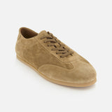 Showcased at an angle against a white background, the COMMON PROJECTS Winter Suede Driving Sneaker features tan suede, brown laces, and a rubber sole—offering luxury low-top design that merges timeless style with casual elegance.