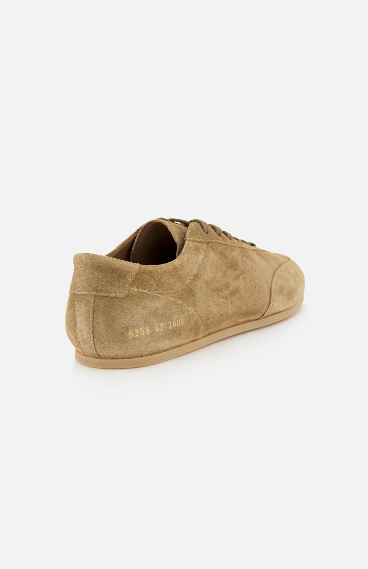 The COMMON PROJECTS Winter Suede Driving Sneaker is shown from the back, featuring tan suede construction in a taupe shade with a gum sole. Distinct gold numbers are stamped near the heel for a refined accent. This luxury low-top showcases visible stitching and laces in a minimalist design.