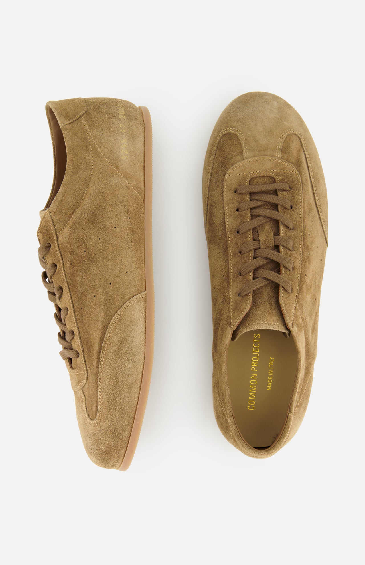 The COMMON PROJECTS Winter Suede Driving Sneaker is a luxurious low-top shoe crafted from tan suede, detailed with brown laces and elegant gold branding inside. Shown from both the side and top view, these sneakers feature distinctive gum soles and combine timeless style with modern sophistication.