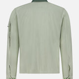 The C.P. COMPANY 50 Fili Two-tone Overshirt in moss green is shown from the back, featuring a dark green collar, buttoned cuffs, and a utilitarian upper left sleeve pocket.