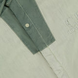 Close-up of the C.P. COMPANY 50 Fili Two-tone Overshirt in moss green, featuring snap buttons, visible white stitching, and an embroidered logo for a refined utilitarian look.