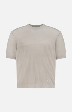 The C.P. COMPANY Flax Crewneck Sweater is a light beige linen knit top with short sleeves and a crew neckline, featuring a small white rectangular label on the left hem, shown against a white background.