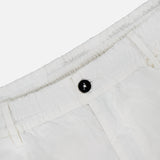 Close-up of the waistband of C.P. COMPANY Micro-Reps Boxy Loose Pants in white high-density cotton, showcasing a black button, elasticized detail, and belt loops against a plain light background.