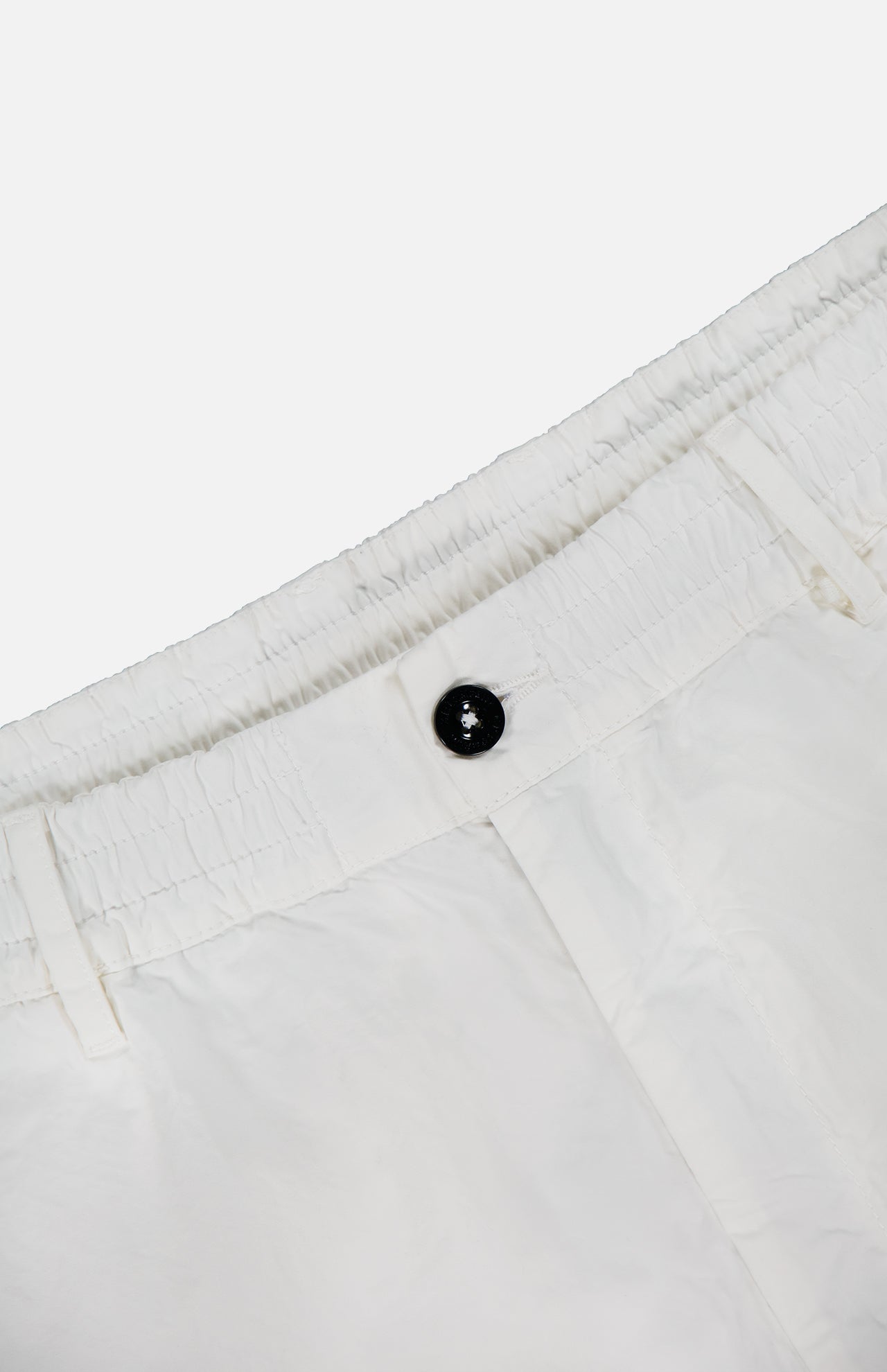 Close-up of the waistband of C.P. COMPANY Micro-Reps Boxy Loose Pants in white high-density cotton, showcasing a black button, elasticized detail, and belt loops against a plain light background.