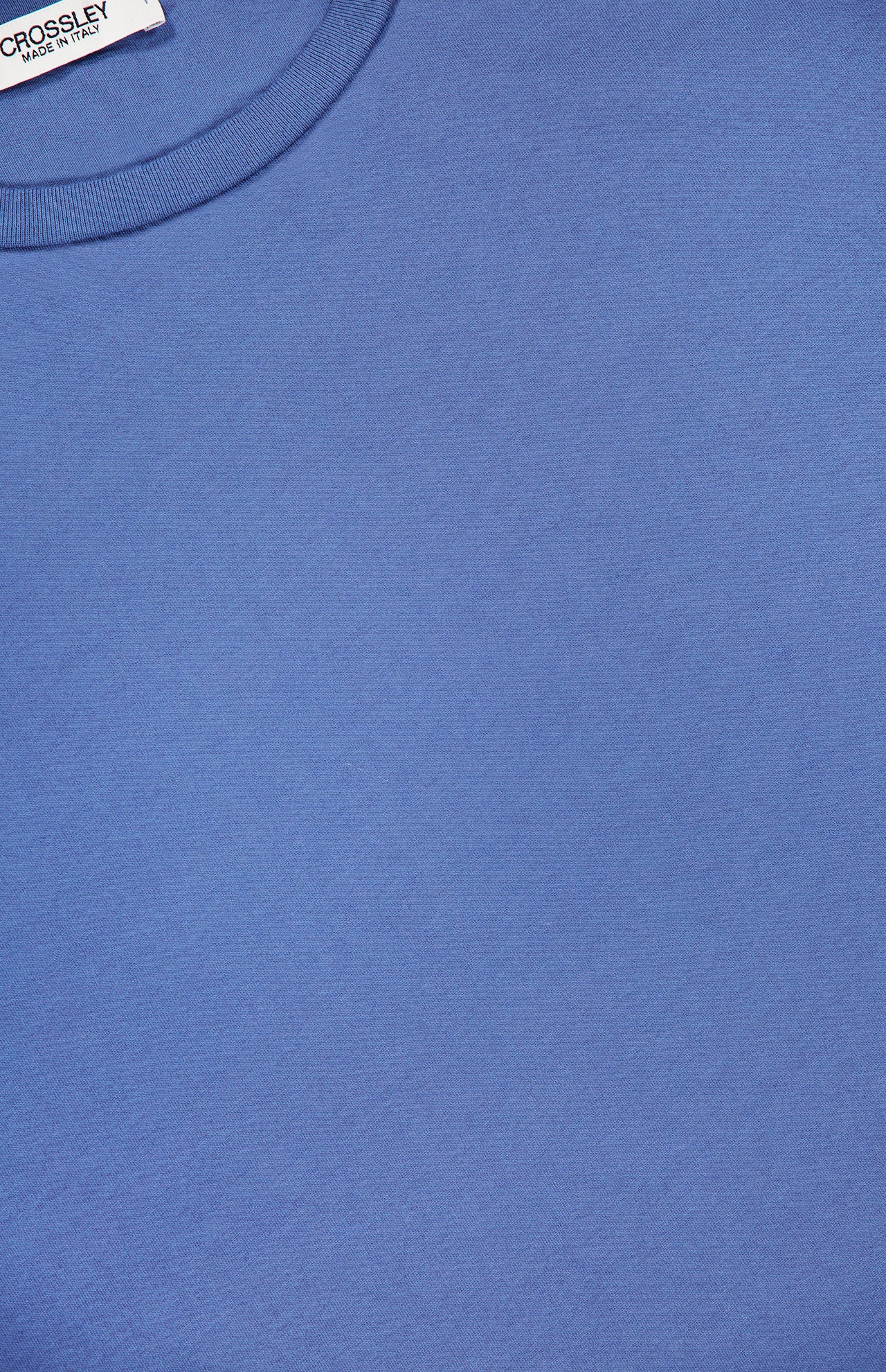 Close-up of the Hunt Cotton Short Sleeve Crew T-shirt by CROSSLEY, featuring a smooth, unpatterned blue fabric and round neckline. A white CROSSLEY label is visible at the top left, highlighting quality Italian knitwear.