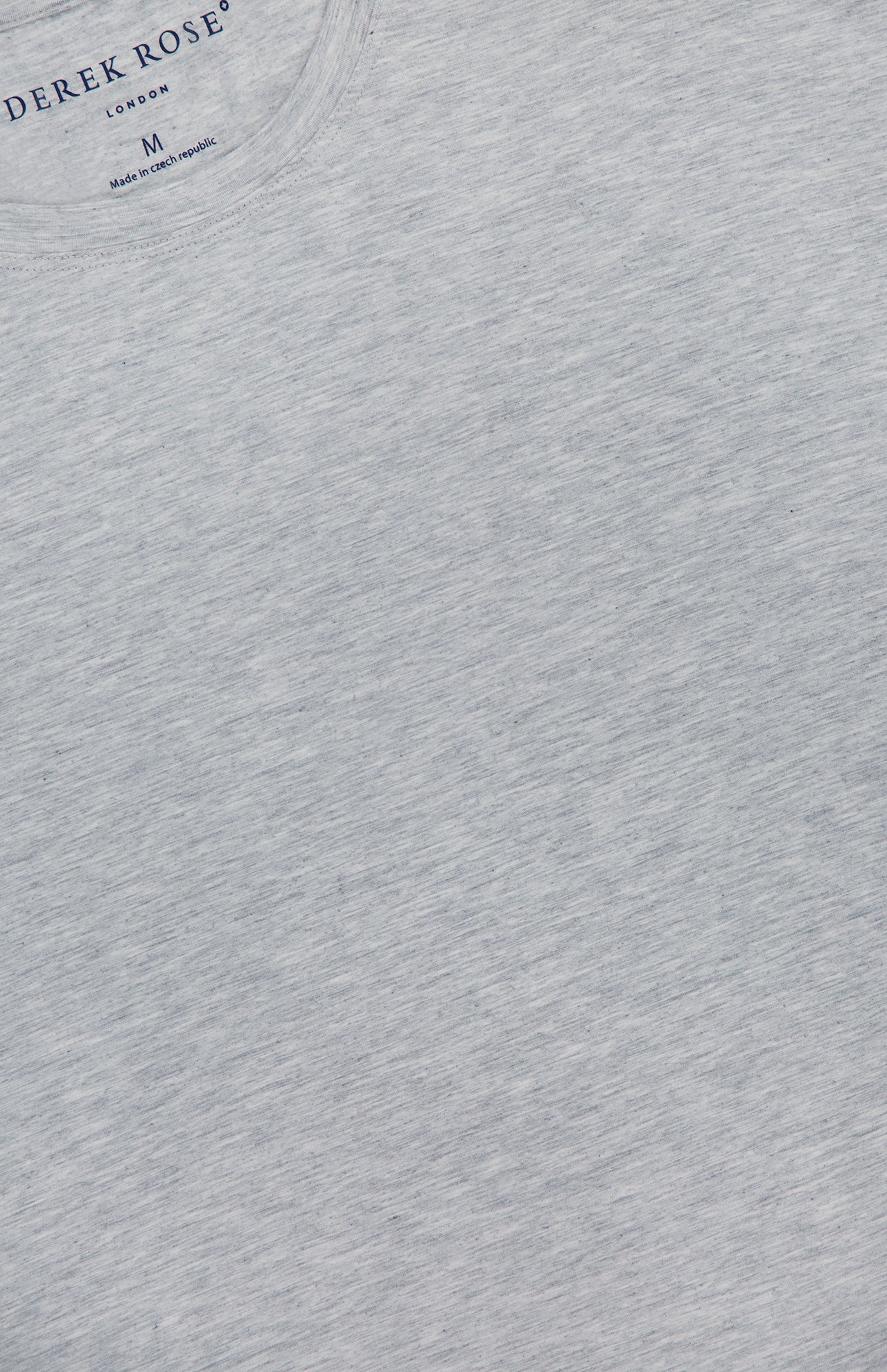 Close-up of a light grey heather Ethan Micro Modal Stretch T-Shirt with a crew neckline. Inside the collar, DEREK ROSE brand, size M, and Made in Czech Republic are printed.