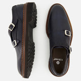 The Mezzaro Bisonte Loafer by DI BIANCO, crafted from dark blue bison leather, features double monk straps with silver buckles and brown soles. The shoes are displayed from the top and side on a white background.