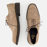 The DI BIANCO Nettuno Suede Lace Up Loafer—a pair of beige dress shoes with wingtip brogue Oxford detailing, brown laces, and decorative perforations—displayed from the side and above on a light background.