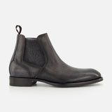 The Osimo Peccary Boot by DI BIANCO is a black leather Chelsea boot featuring elastic side panels, a pull tab, low stacked heel, and rounded toe, shown in a side profile on a plain white background.