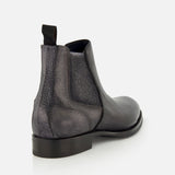 The Osimo Peccary Boot by DI BIANCO is shown from the back left, highlighting its black grained leather, heel, sole, and pull tab against a plain white background.