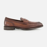 The DI BIANCO Tombolo California Slip On Loafer, shown in side profile against a white background, features brown leather, a low heel, visible stitching, and a penny slot detail. This classic loafer is expertly crafted in Italy.