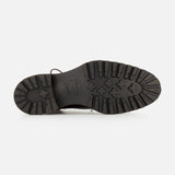 The image shows the bottom view of the DI BIANCO Torino Calfskin Suede Boot, featuring a black sole with deep, rugged treads and a central logo, reminiscent of military-style boots and designed for enhanced grip and durability.