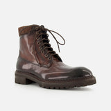 The DI BIANCO Torino Calfskin Suede Boot—a single dark brown lace-up boot with a rugged sole and padded collar, handmade in Italy—is displayed against a light gray background.